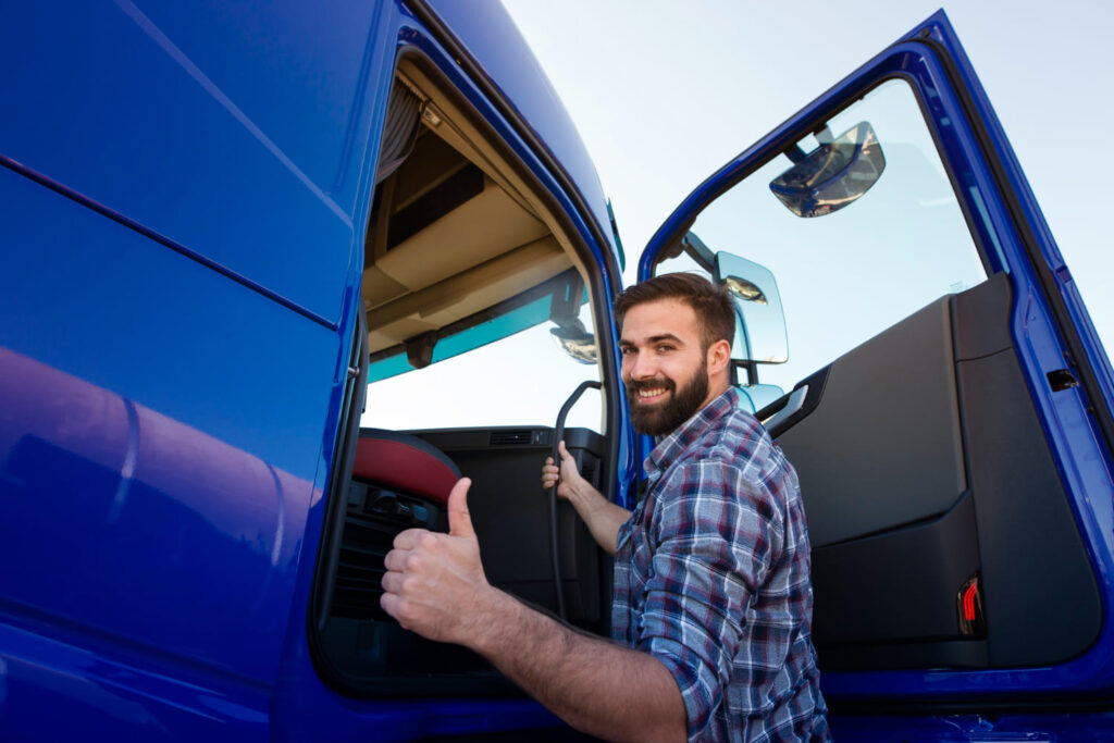 conductor de camion sentado en cabina mostrando pulgar arriba y sonriendo
